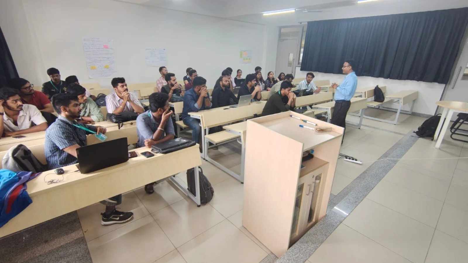 A full classroom of college students attending a practical AI workshop with Rakesh Mondal presenting at the front